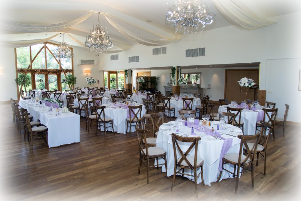 Wedding reception set up with lilac cheesecloth table runners, lilac and ivory high centrepieces and matching top table florals at Mythe Barn