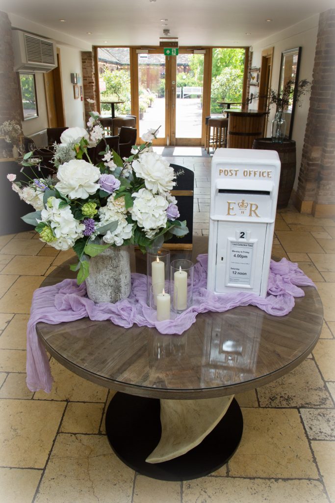a ROYAL MAIL IVORY WEDDING CARD POSTBOX WITH CANDLES IN CYLINDER VASES AND A LILAC CHEESECLOTH TABLE RUNNER