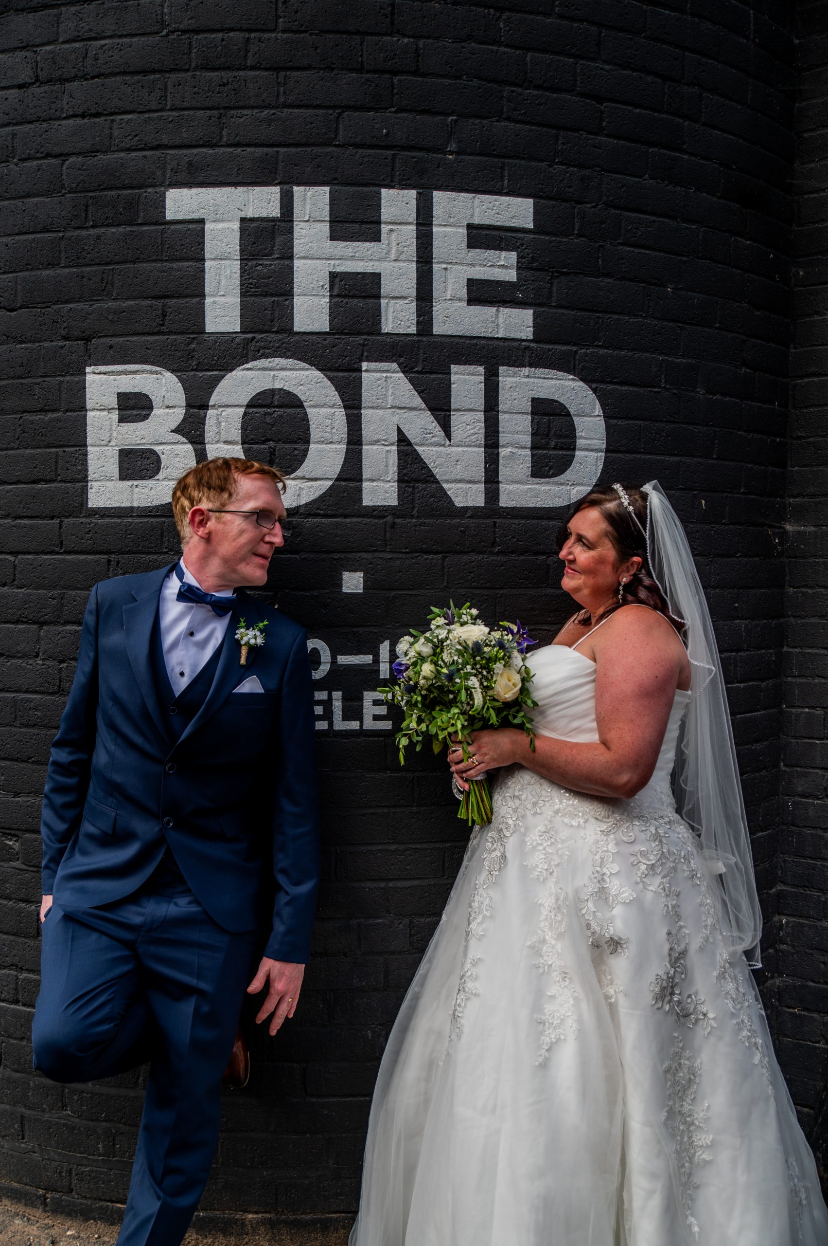 Bride and groom stood in front of a sign that says The Bond