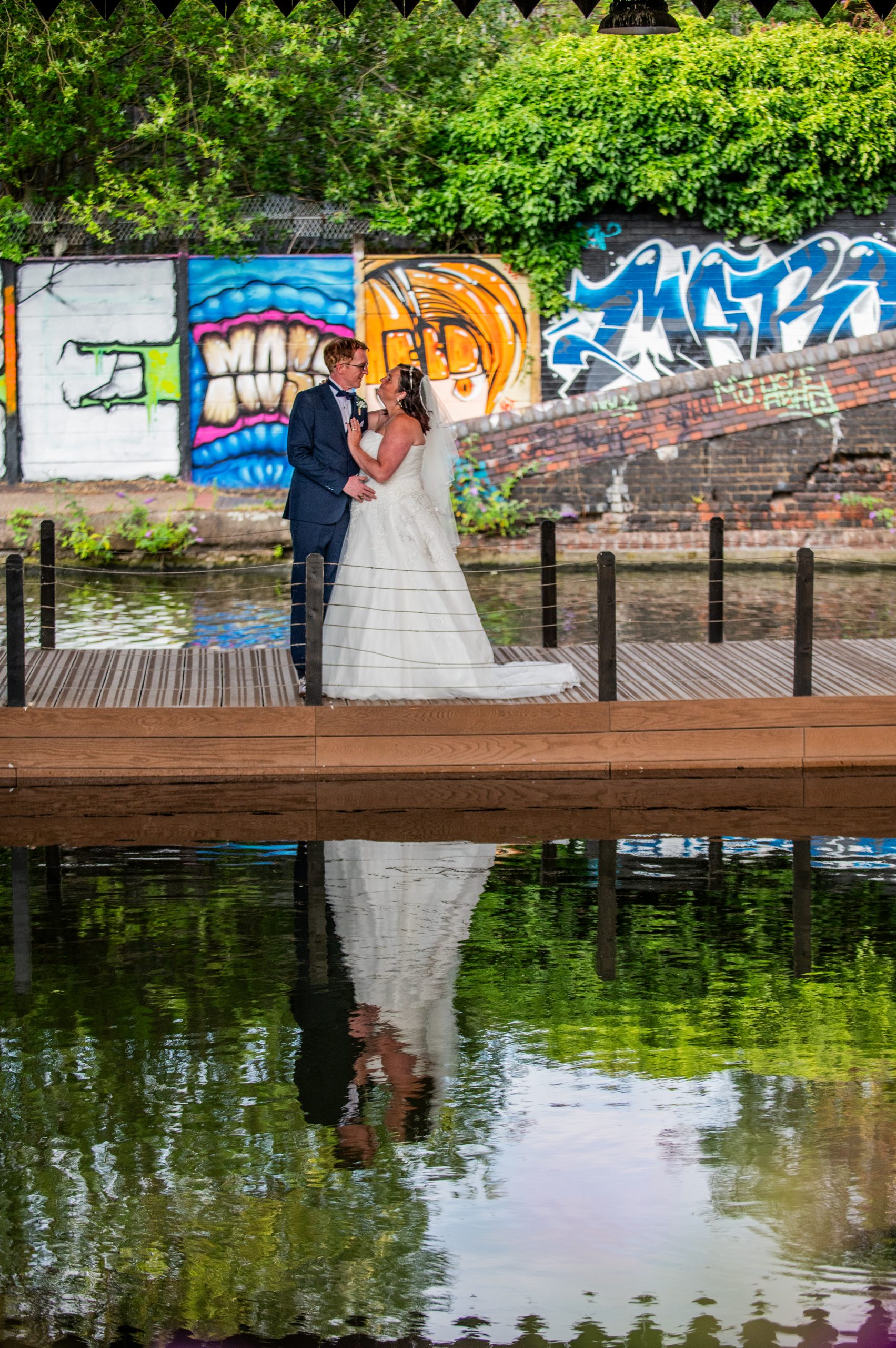 Bride and groom stand in front of a graffiti wall