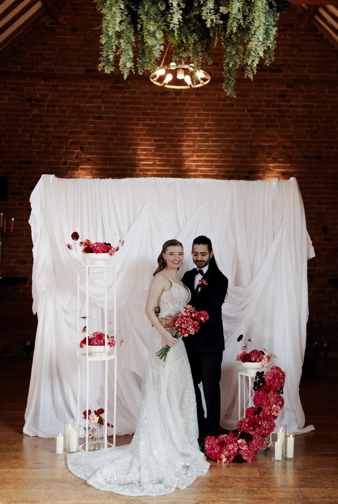 bride and groom, drapery backdrop and fresh florals