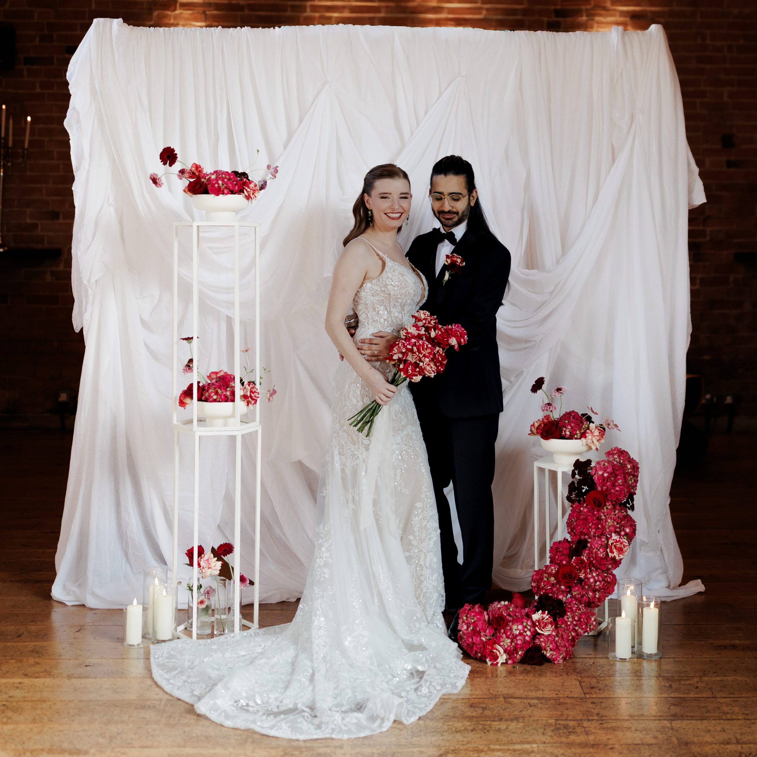 bride and groom, drapery backdrop and fresh florals